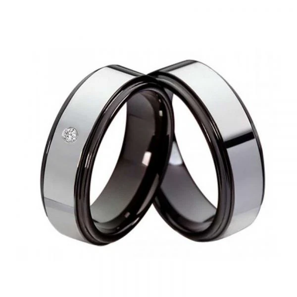 Paar Wolfram‑Partnerringe mit glänzender Oberfläche, ein Ring mit funkelndem Zirkonia‑Steinbesatz, beide Ringe mit schwarzem Rand und Platz für Lasergravur innen und außen.