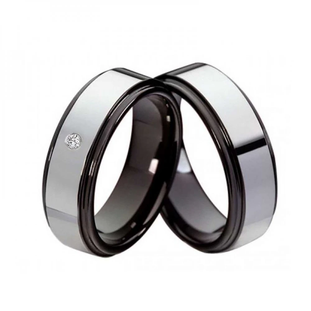 Paar Wolfram‑Partnerringe mit glänzender Oberfläche, ein Ring mit funkelndem Zirkonia‑Steinbesatz, beide Ringe mit schwarzem Rand und Platz für Lasergravur innen und außen.
